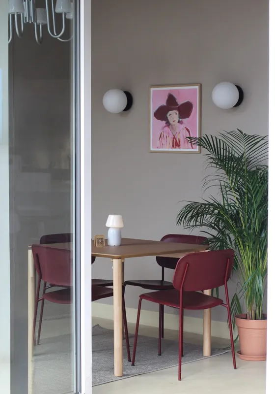 Dining table with burgundy chairs and a palm by the window